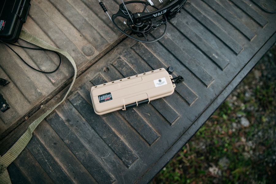 Tan broadhead case on a wooden deck beside a bow