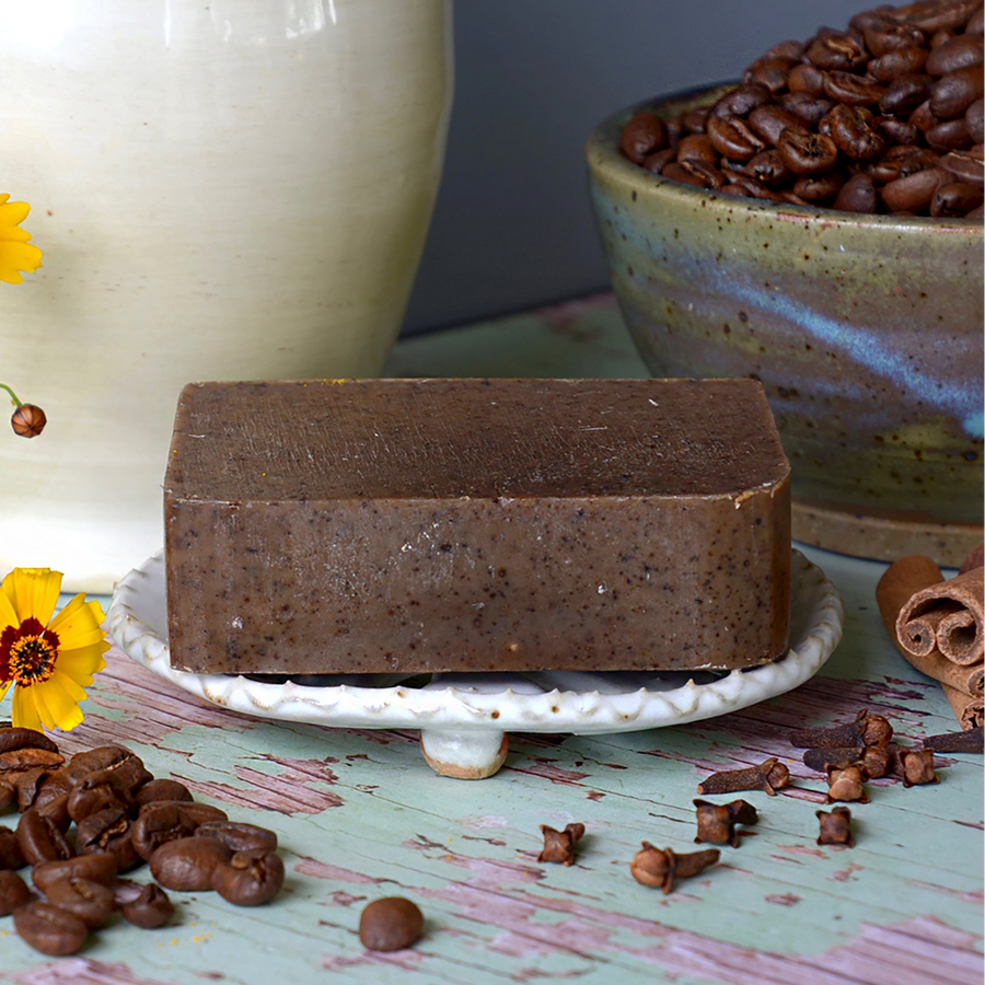Brown spiced coffee soap bar beside coffee beans and whole spices