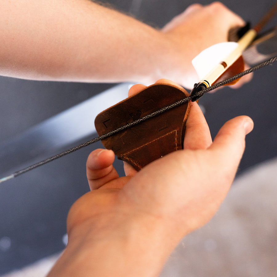YES Tab 3-Under Archery Finger Tab — tab held behind a nocked arrow