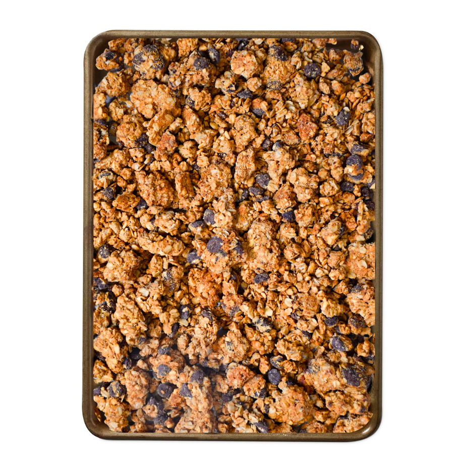 Peanut Butter Dark Chocolate Granola - peanut and chocolate granola spread across a baking tray