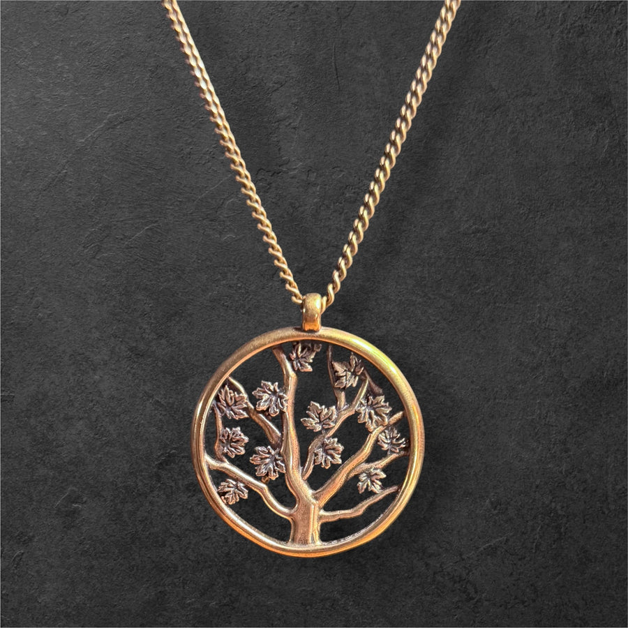 Tree of Life pendant on curb chain against dark stone