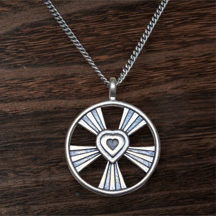 Shining Heart pendant with openwork rays against wood