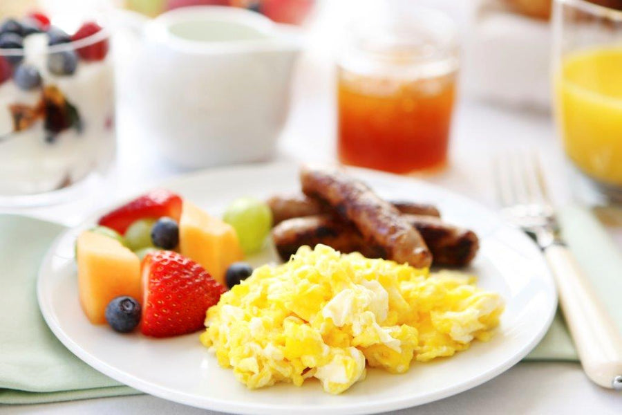 Breakfast with eggs, sausage, toast and fruit, serving suggestion