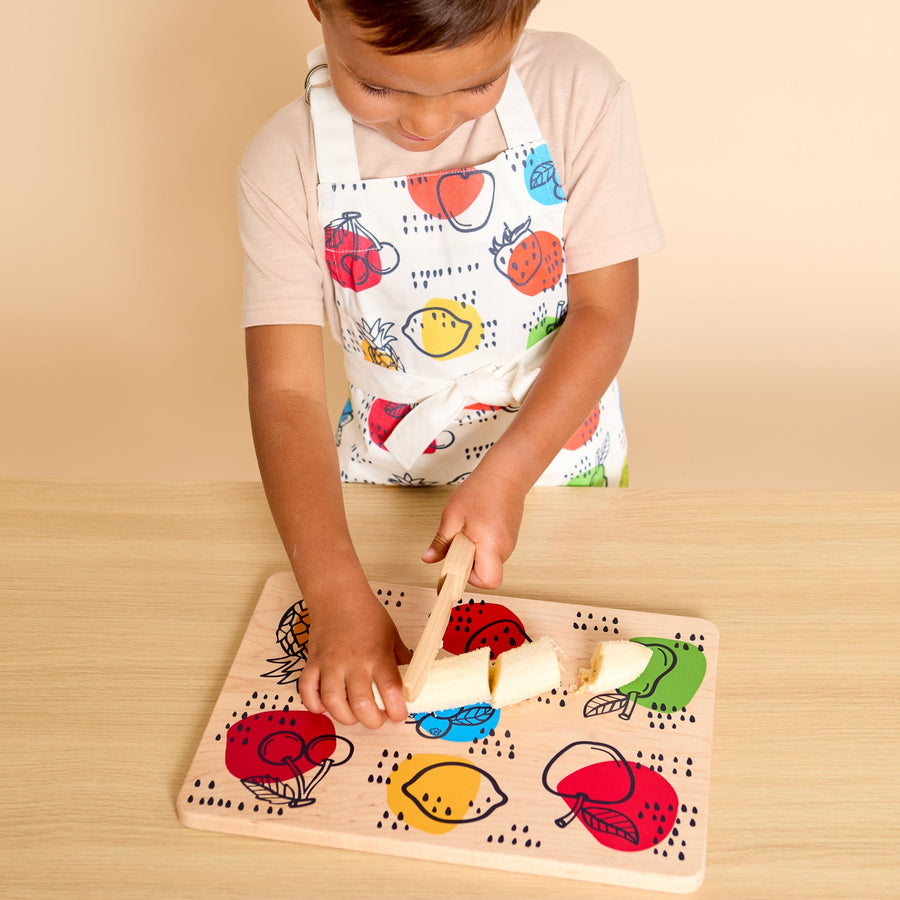 Child using a wooden knife and illustrated cutting board during food preparation