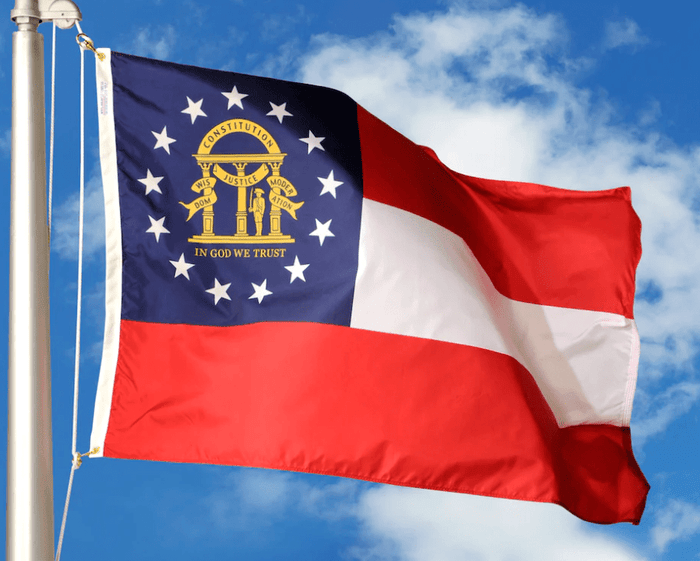 Georgia state flag flying from an outdoor flagpole against a blue sky