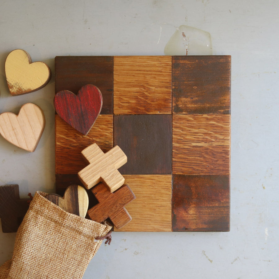 Wooden tic-tac-toe board with heart and X playing pieces.