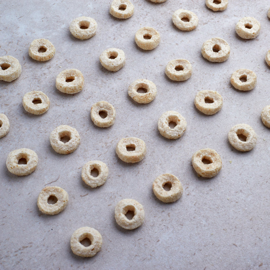 Honey Nut Protein Cereal: cereal pieces on a pale surface.