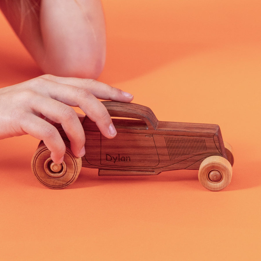 Child’s hands pushing a wooden toy car on a tabletop
