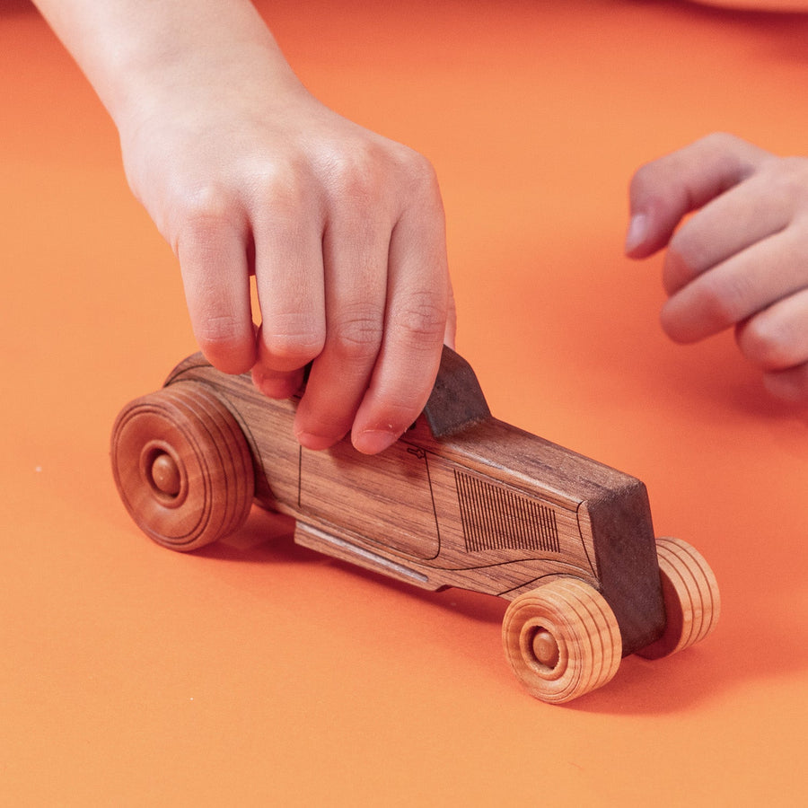 Child’s hands pushing a wooden toy car on a tabletop