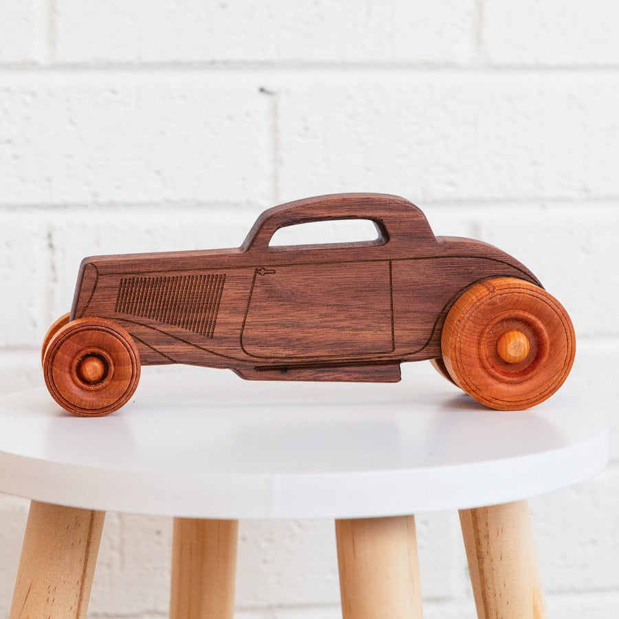 Natural wood hot rod toy car displayed on a round table
