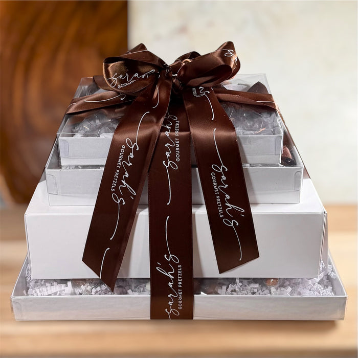 Stacked white gift boxes tied with a brown branded ribbon