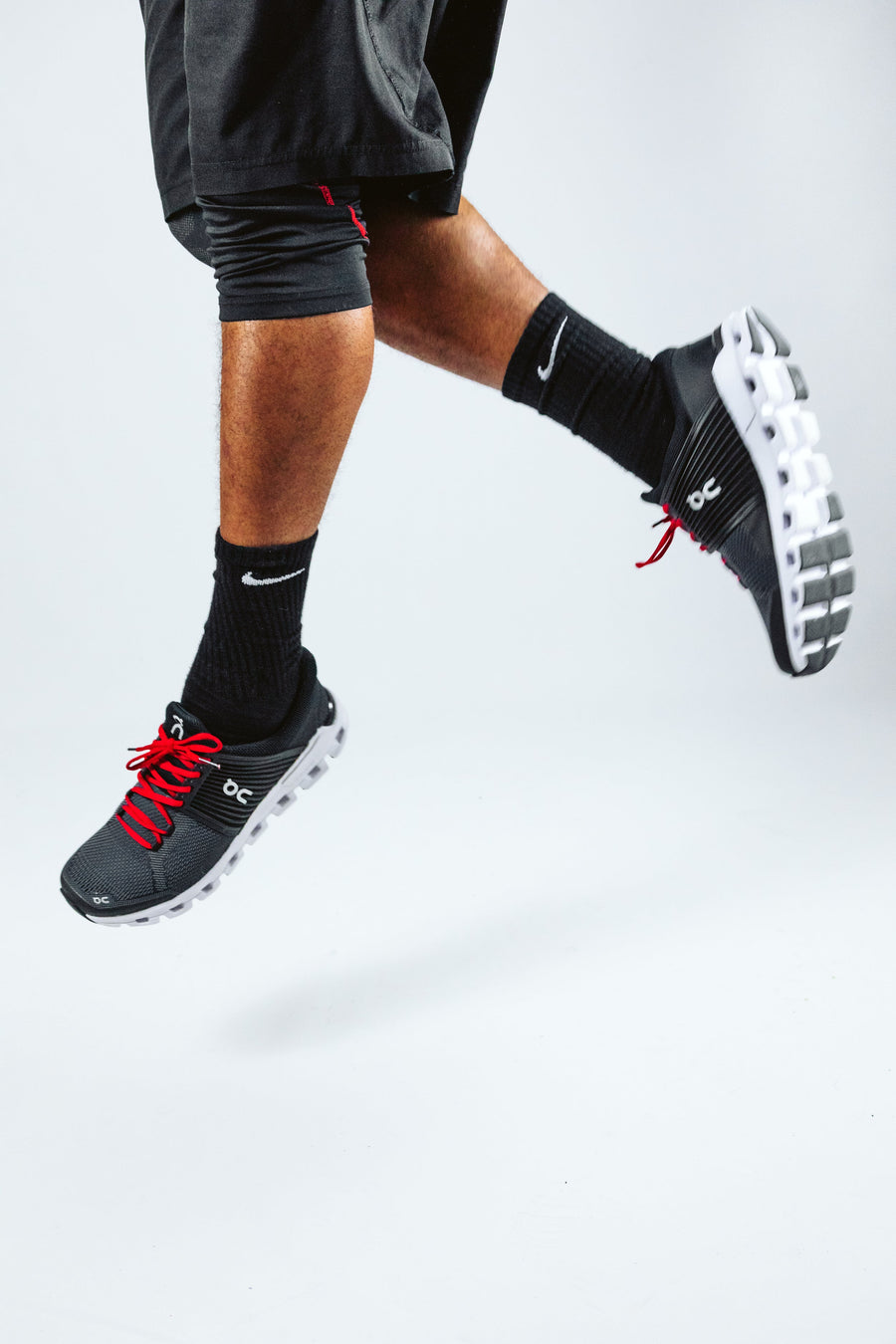 Red oval athletic shoelaces worn with black athletic shoes outdoors