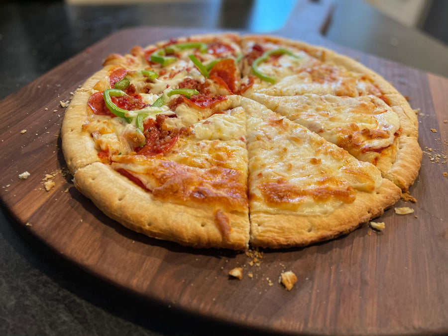 Homemade pizza served on a walnut pizza peel