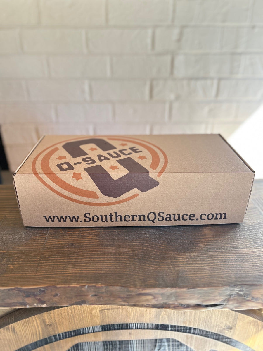 Closed kraft Whole Hog sauce gift box with Q Sauce logo