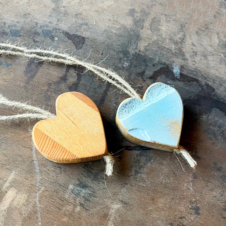 Natural and blue wooden heart charms resting on a rustic surface.