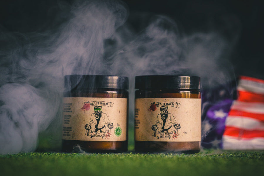 Two After Action Beast Balm jars on turf with mist and an American flag