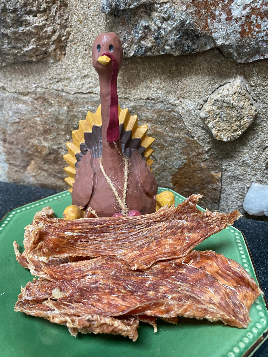 Turkey breast jerky strips on a green plate beside a turkey figurine