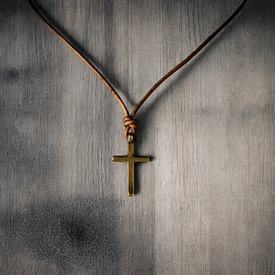 Classic Cross pendant and leather cord hanging against wood