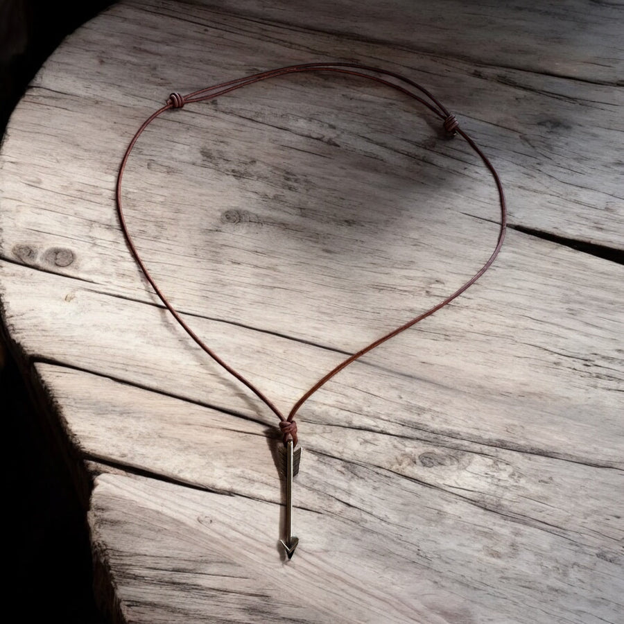 Full view of adjustable leather cord and arrow pendant on wood