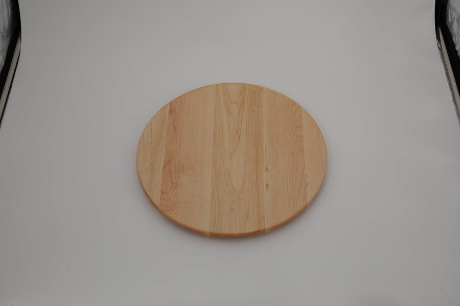 Round maple board standing against a wall beside kitchen equipment
