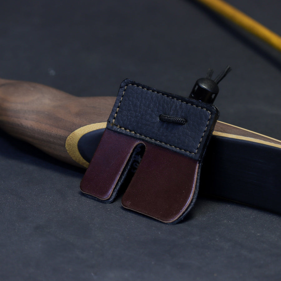Shell Cordovan Split-Finger Archery Tab — cordovan tab beside bowstring