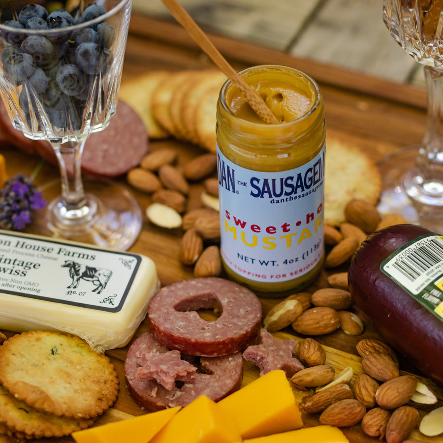 Sliced sausage, cheese, crackers and nuts beside a Sweet Hot Mustard jar; serving suggestion