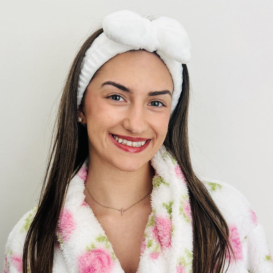 Woman wearing a white plush bow headband during a skincare routine