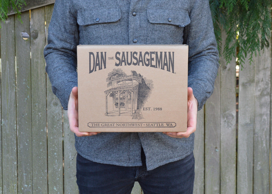 Person holding a closed Dan The Sausageman kraft gift box
