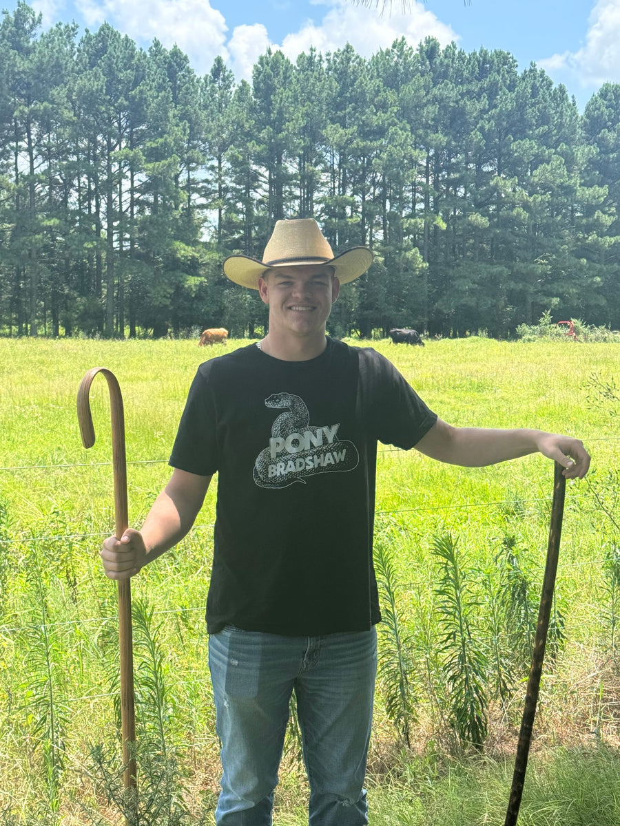 Person outdoors holding a curved staff and a separate straight hiking stick