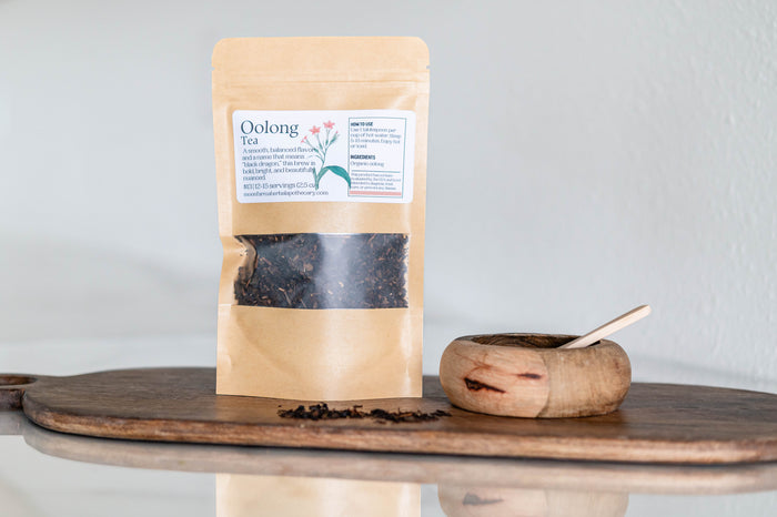 Pouch of loose-leaf oolong tea beside a wooden scoop
