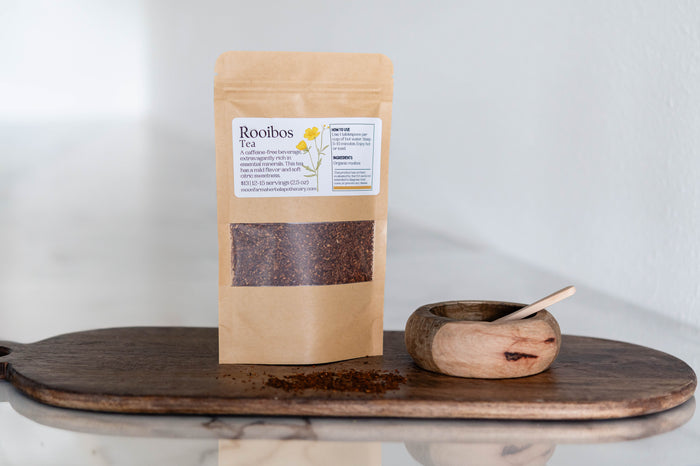 Pouch of loose-leaf rooibos tea beside a scoop