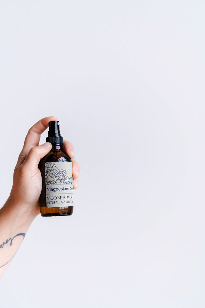 Hand spraying an amber bottle of magnesium body spray