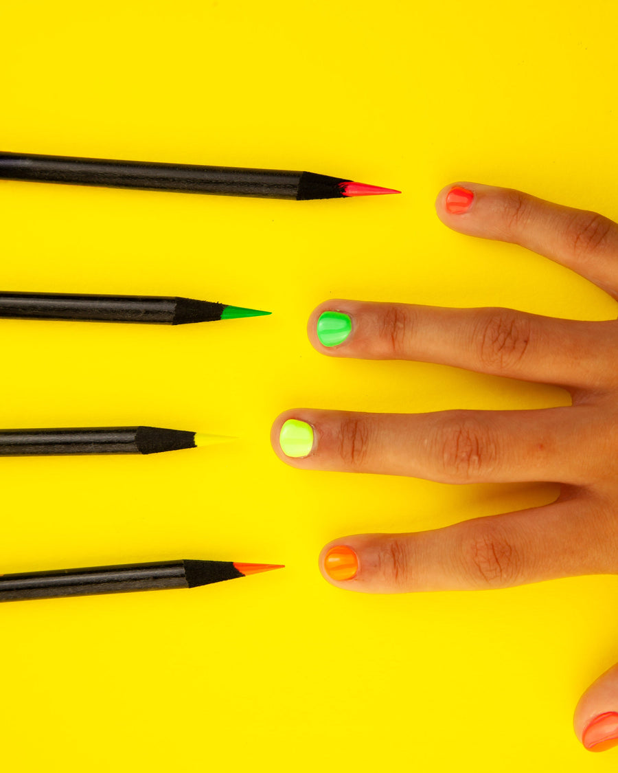 Four highlighter pencils beside matching painted fingernails on yellow