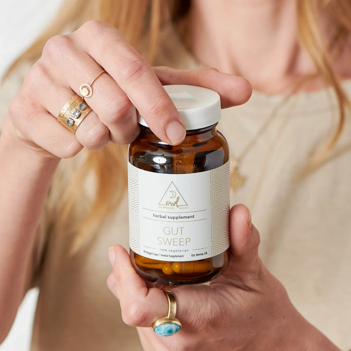 Person opening a Gut Sweep capsule bottle