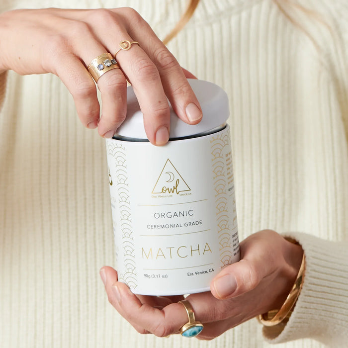 Hands holding a lidded tin of Organic Matcha Powder