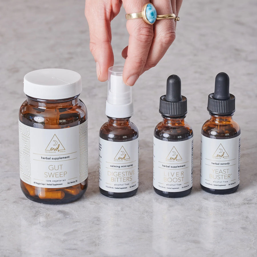 Hand reaching toward a spray in a four-product supplement assortment