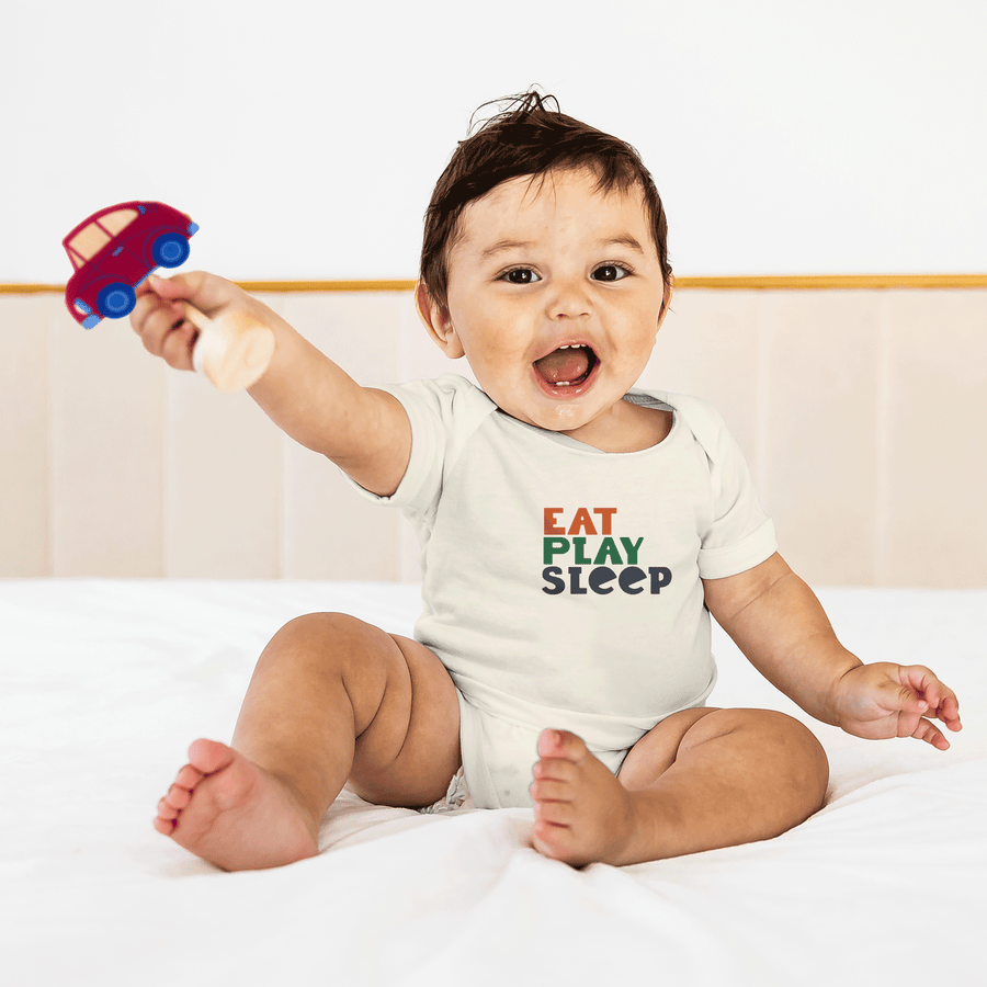 Baby wearing a cream Eat Play Sleep cotton bodysuit and holding a car rattle