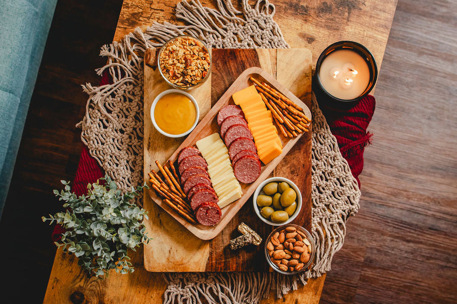 Overhead view of sausage, cheese, pretzels, olives, nuts and mustard; board not included