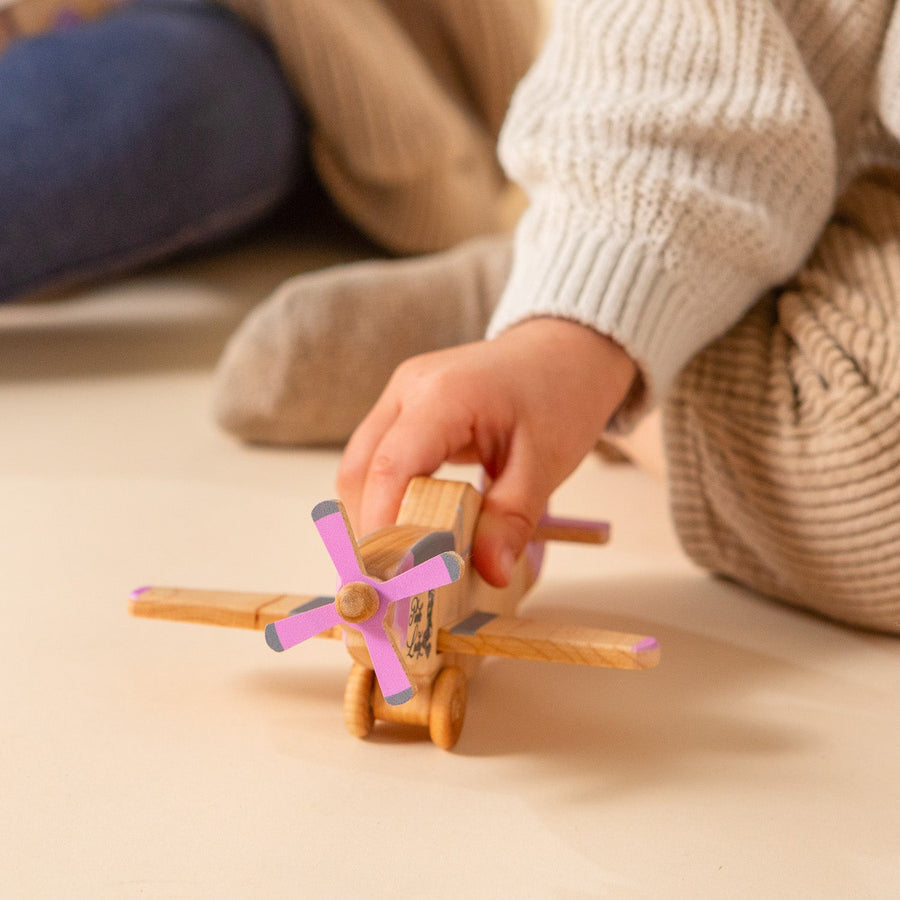 Child’s hands holding and guiding a wooden toy airplane