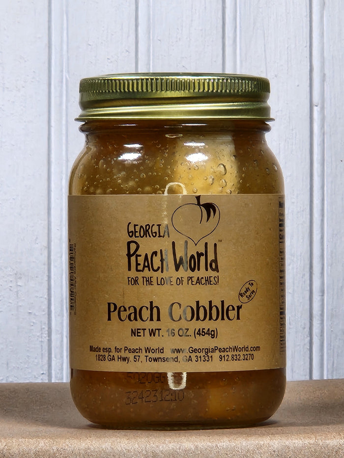 Peach cobbler dessert in a glass jar with a gold lid and a brown label.