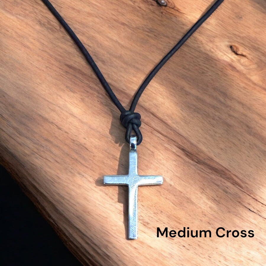 Medium Classic Cross pendant on leather cord against wood