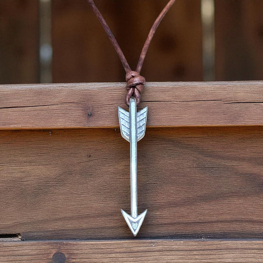 Arrow necklace hanging against a wooden background
