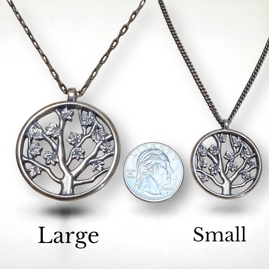 Large and small Tree of Life pendants compared beside a coin