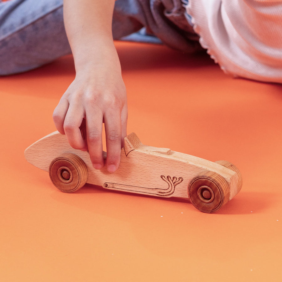 Child’s hands pushing a wooden toy car on a tabletop