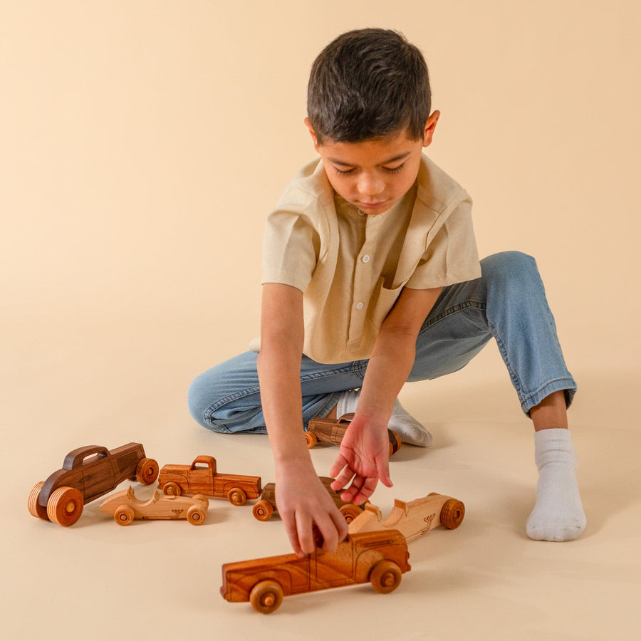 Children playing with an assortment of wooden cars, trucks and airplanes