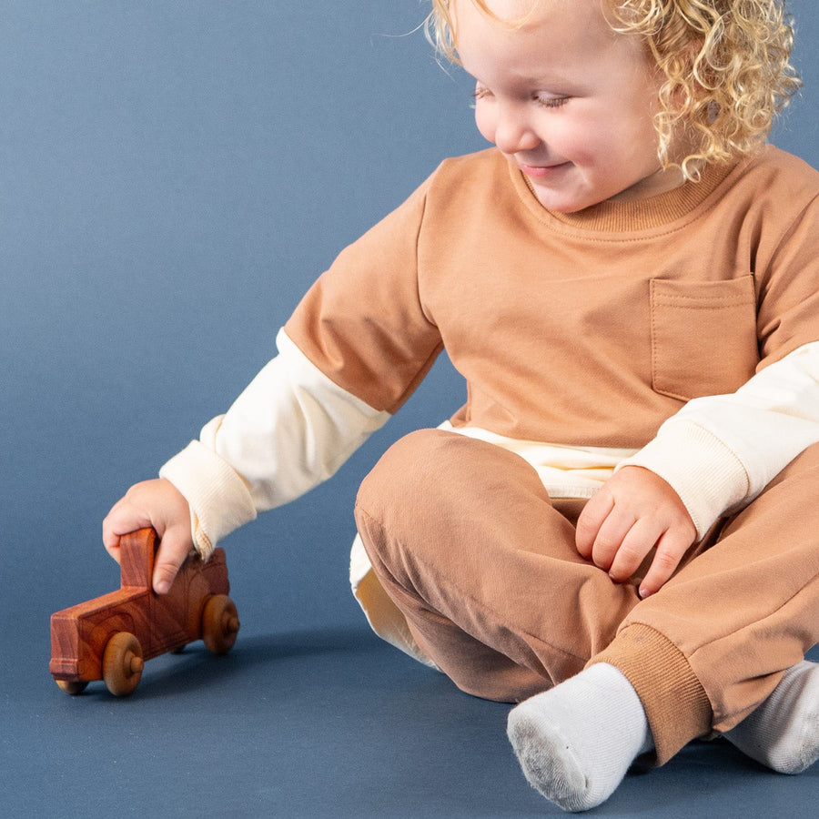 Child sitting on the floor and playing with wooden toy vehicles