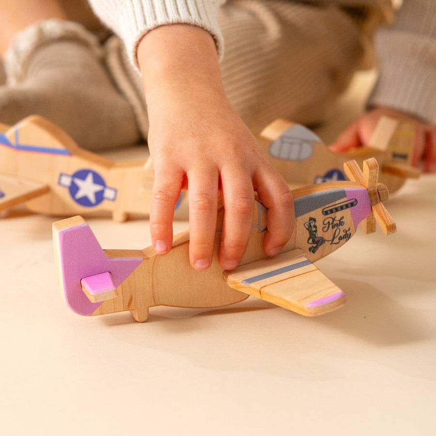 Child’s hands holding and guiding a wooden toy airplane