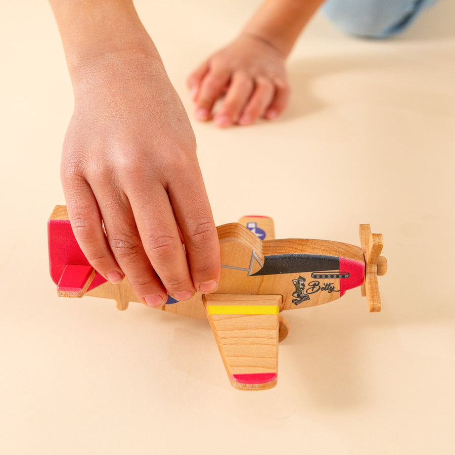 Child’s hands holding and guiding a wooden toy airplane