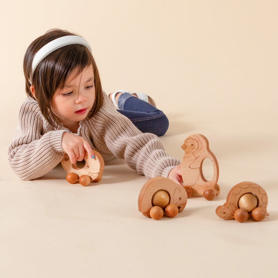 Children exploring wooden animal push toys with spherical wheels