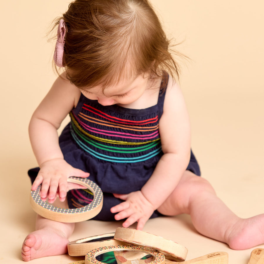 Child holding a round wooden-framed discovery mirror